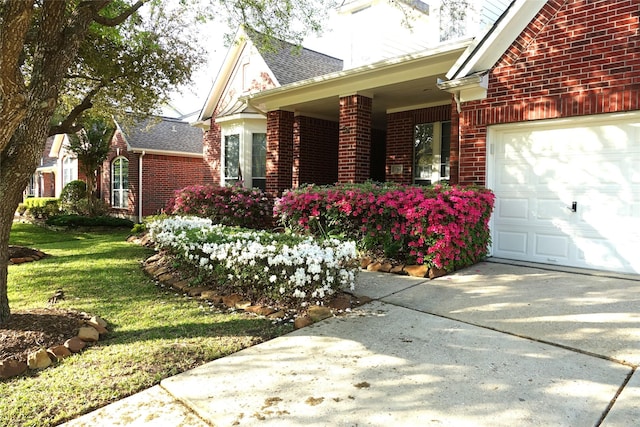 view of home's exterior featuring an attached garage, brick siding, covered porch, a yard, and driveway