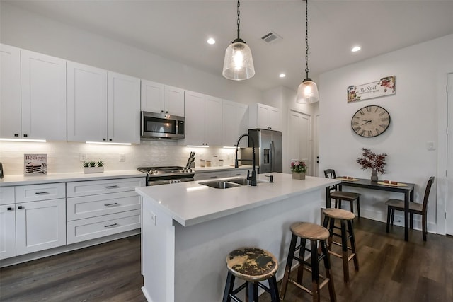 kitchen featuring visible vents, a sink, dark wood finished floors, appliances with stainless steel finishes, and backsplash
