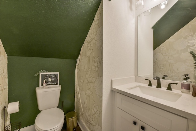 full bath with vanity, wallpapered walls, vaulted ceiling, and toilet