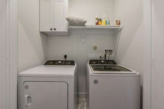 clothes washing area with separate washer and dryer and cabinet space