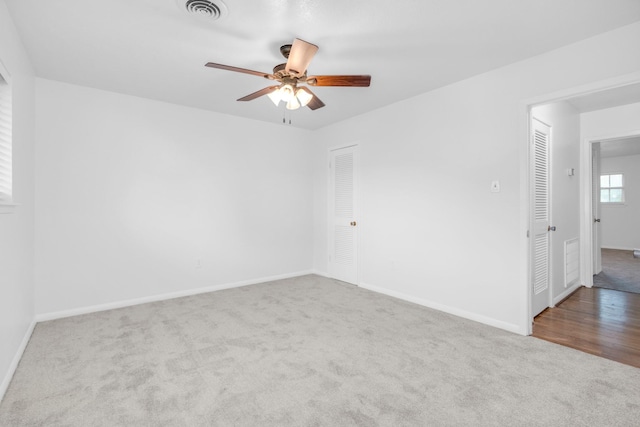 carpeted spare room featuring baseboards, visible vents, and a ceiling fan