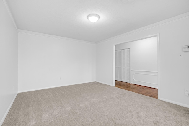 unfurnished room with baseboards, crown molding, and carpet flooring
