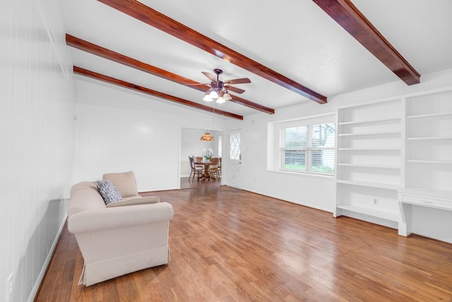 living room featuring wood finished floors, lofted ceiling with beams, a ceiling fan, and baseboards