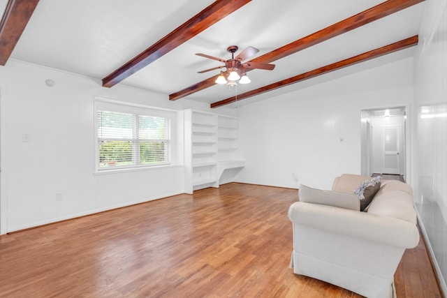 living area featuring beamed ceiling, ceiling fan, and light wood-style flooring