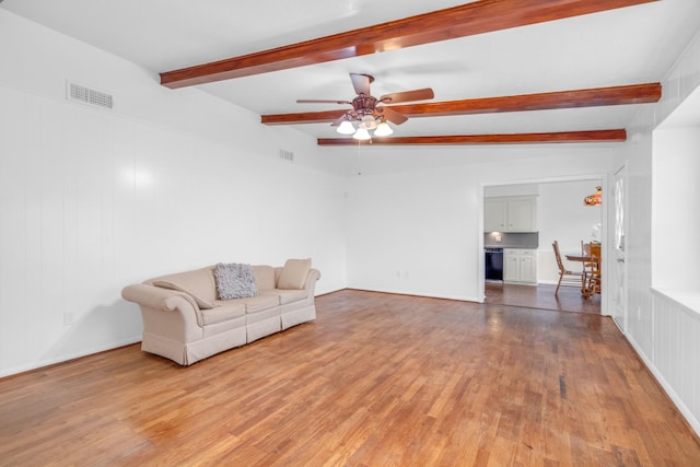 living area with beamed ceiling, a ceiling fan, visible vents, and light wood-style flooring