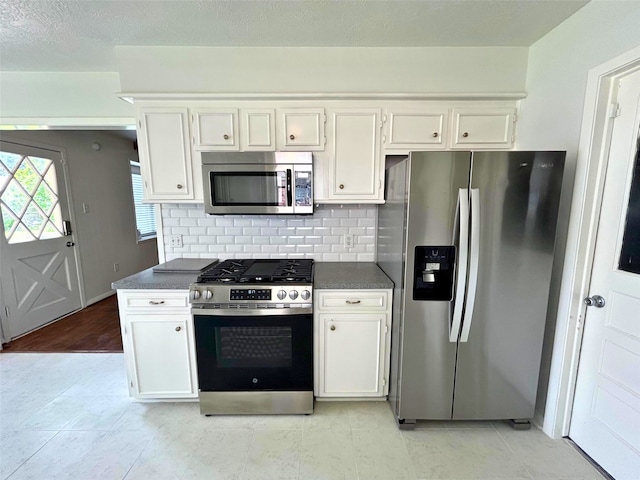 kitchen featuring dark countertops, white cabinets, backsplash, and stainless steel appliances