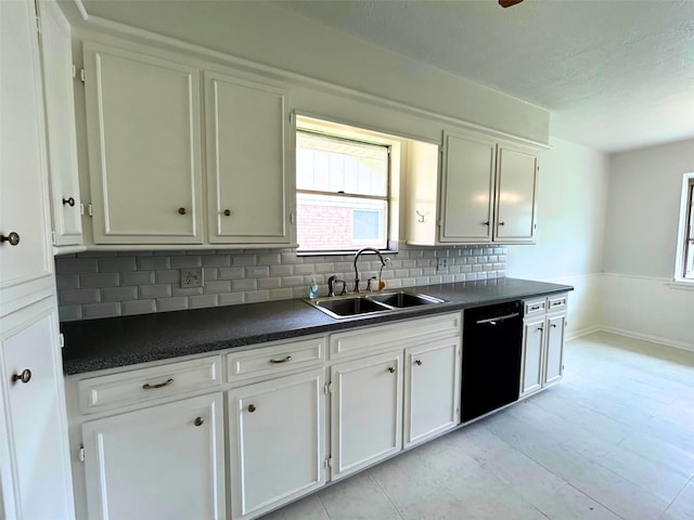 kitchen featuring decorative backsplash, white cabinets, a sink, dark countertops, and black dishwasher