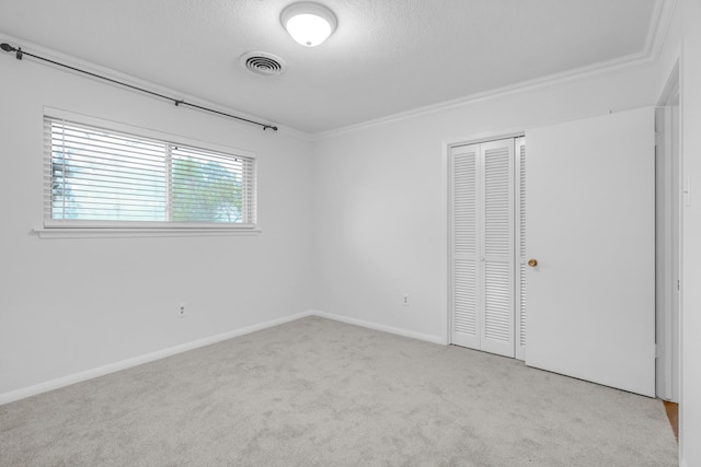 unfurnished bedroom featuring visible vents, carpet floors, a closet, and crown molding