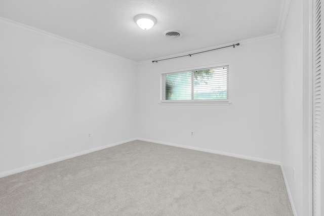 carpeted spare room featuring crown molding, visible vents, and baseboards