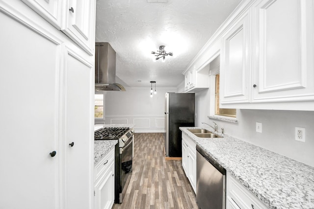 15030 Royal Shadows Dr, Houston, TX 77082 - kitchen with a sink, stainless steel appliances, wall chimney exhaust hood, white cabinetry, and a textured ceiling