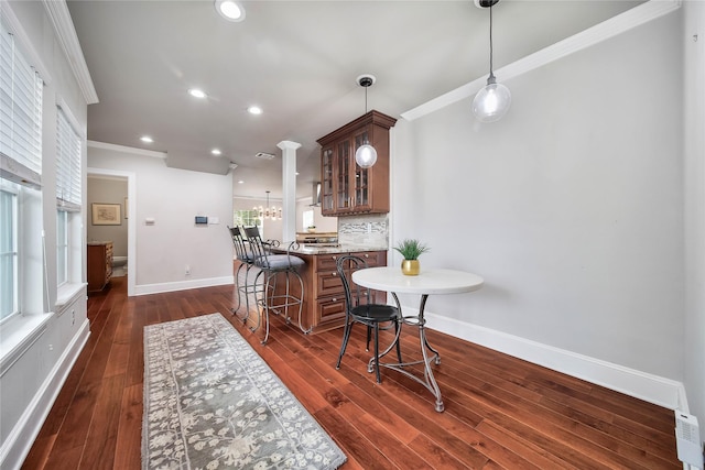 3327 Palm St, Houston, TX 77004 - kitchen featuring crown molding, a kitchen breakfast bar, glass insert cabinets, baseboards, and tasteful backsplash