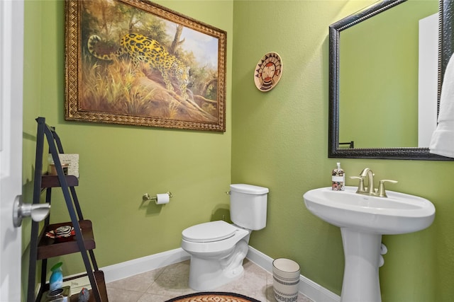 half bath featuring a sink, tile patterned floors, baseboards, and toilet