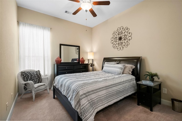 carpeted bedroom featuring baseboards, visible vents, multiple windows, and ceiling fan