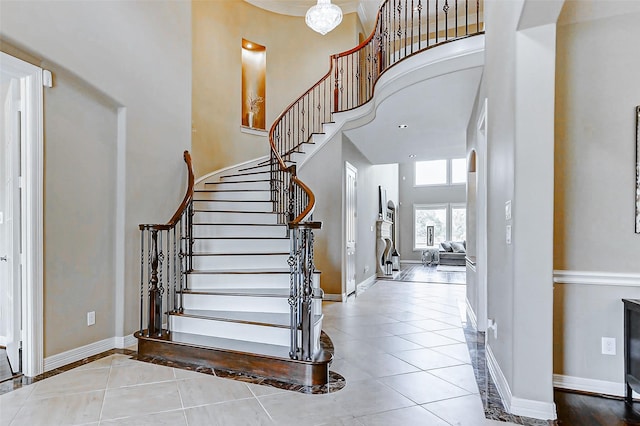 stairs with a towering ceiling, tile patterned flooring, and baseboards