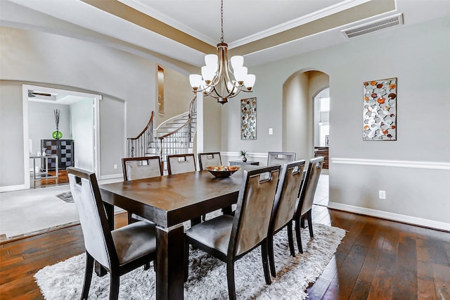 dining area with stairway, a notable chandelier, visible vents, arched walkways, and hardwood / wood-style floors