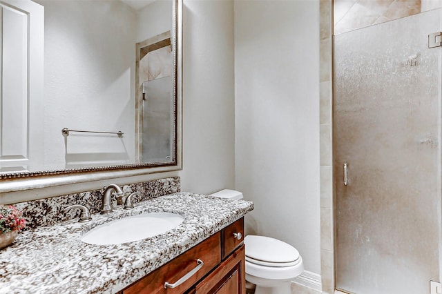 bathroom featuring a shower stall, toilet, and vanity