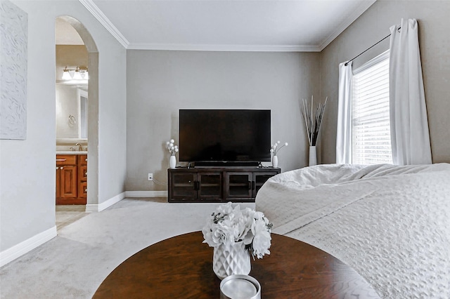 bedroom featuring a sink, baseboards, arched walkways, ornamental molding, and light carpet