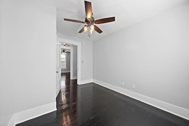 unfurnished room featuring a ceiling fan, baseboards, and dark wood-type flooring
