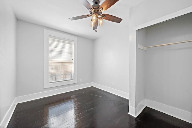 unfurnished bedroom with dark wood-type flooring, ceiling fan, a closet, and baseboards