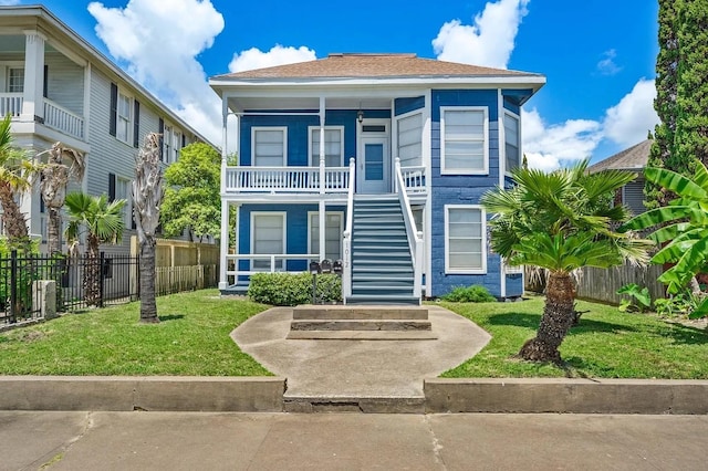 view of front of property with a porch, fence, stairs, and a front lawn
