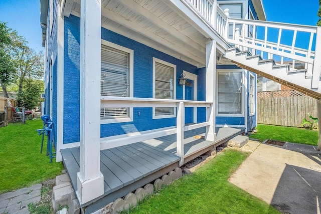 view of side of home featuring stairway, fence, and a lawn