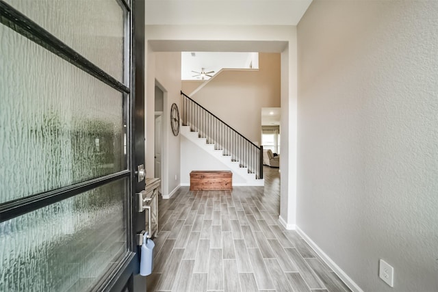 foyer with wood finished floors, ceiling fan, stairs, and baseboards