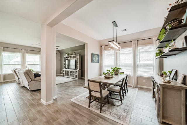 dining space with visible vents, light wood-type flooring, a chandelier, and baseboards