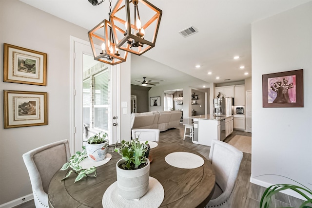 dining space featuring recessed lighting, visible vents, baseboards, wood finished floors, and ceiling fan with notable chandelier