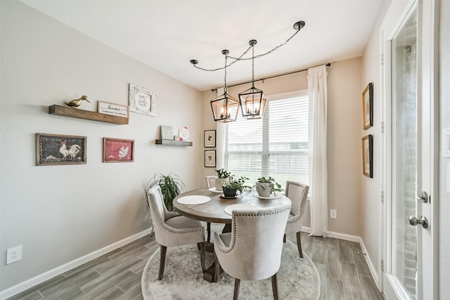 dining room with an inviting chandelier, wood finish floors, and baseboards