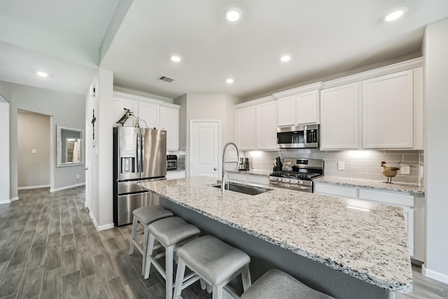 kitchen featuring backsplash, a kitchen bar, a sink, and appliances with stainless steel finishes