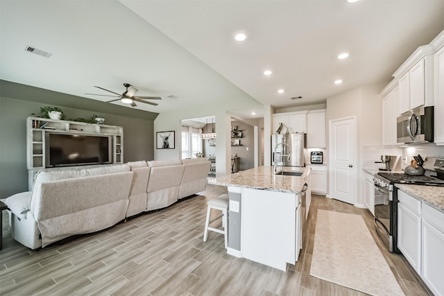 kitchen featuring light stone counters, appliances with stainless steel finishes, white cabinets, visible vents, and a ceiling fan