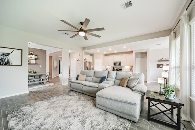 living area with baseboards, visible vents, ceiling fan, and light wood-style floors