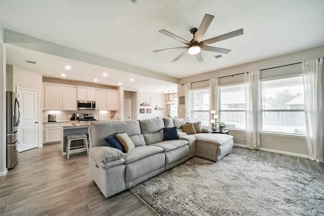 living area featuring ceiling fan, visible vents, baseboards, light wood-type flooring, and recessed lighting