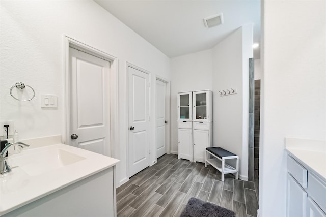 full bathroom featuring visible vents, two vanities, wood finished floors, and a sink
