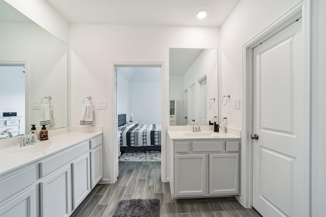 ensuite bathroom featuring two vanities, ensuite bath, wood finished floors, and a sink