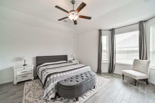 bedroom featuring visible vents, vaulted ceiling, wood finished floors, and baseboards