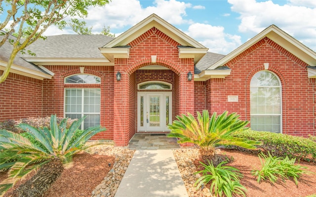 property entrance featuring a shingled roof and brick siding
