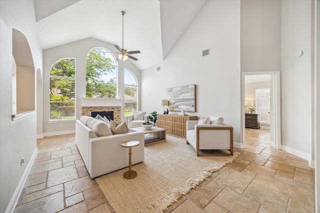living room with stone tile flooring, ceiling fan, visible vents, and high vaulted ceiling