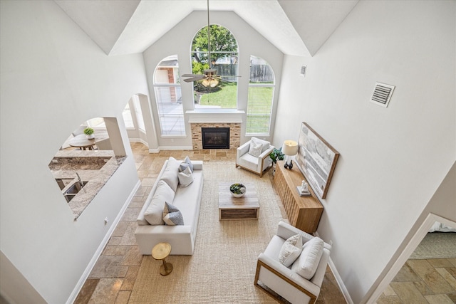 living room with baseboards, visible vents, a ceiling fan, and stone tile floors