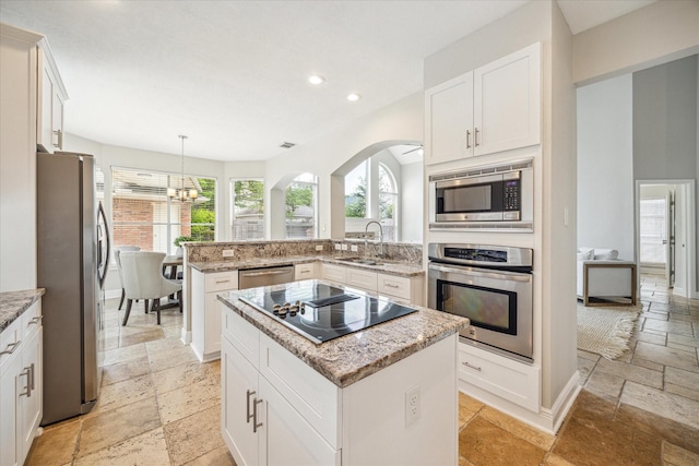 kitchen featuring appliances with stainless steel finishes, arched walkways, stone tile flooring, a notable chandelier, and recessed lighting