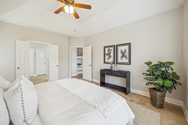bedroom featuring a tray ceiling, baseboards, a ceiling fan, and stone tile floors