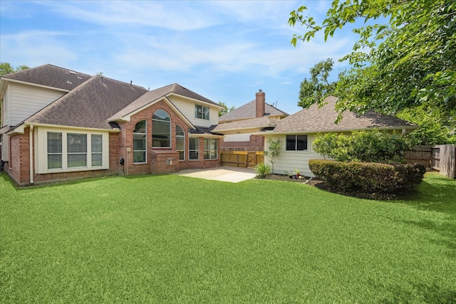 back of house featuring fence, a lawn, a patio area, and brick siding