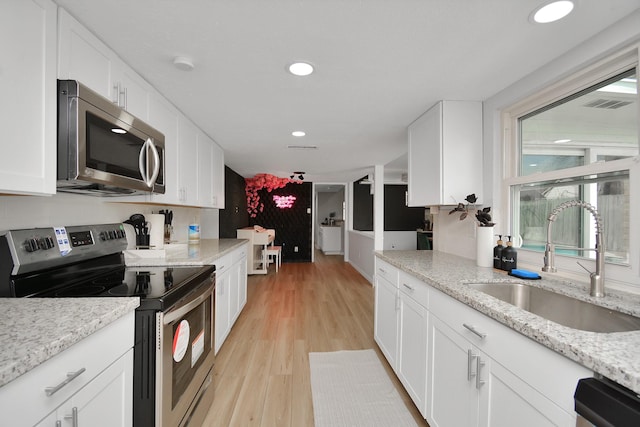 kitchen with white cabinetry, a sink, stainless steel appliances, light wood-type flooring, and recessed lighting