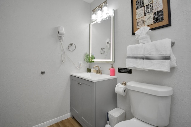 bathroom featuring wood finished floors, toilet, and vanity