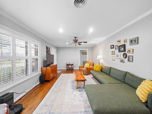 living room with light wood-style floors, ceiling fan, visible vents, baseboards, and ornamental molding