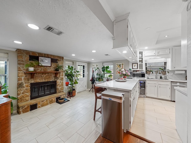 kitchen featuring visible vents, stainless steel appliances, plenty of natural light, and a stone fireplace