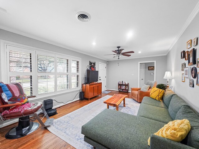 living room with wood finished floors, ceiling fan, crown molding, and visible vents