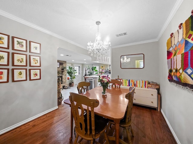 dining space featuring visible vents, ornamental molding, wood finished floors, and a notable chandelier