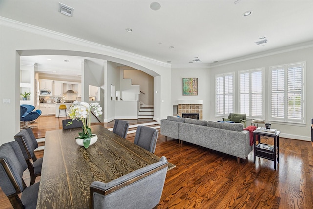 dining area with stairway, a tiled fireplace, ornamental molding, and visible vents