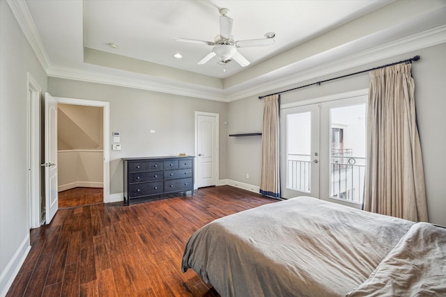 bedroom featuring baseboards, access to outside, a tray ceiling, and wood finished floors